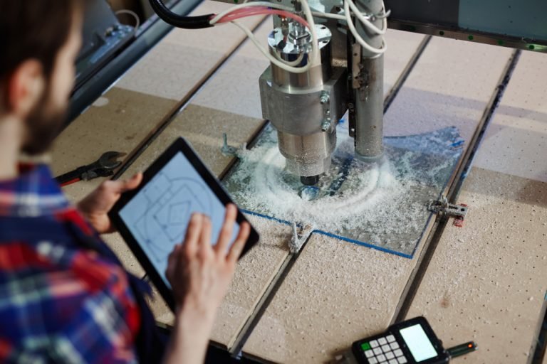A technician using a digital tablet to guide a CNC router machine while it cuts material, creating precision shapes in a Mississauga workshop.